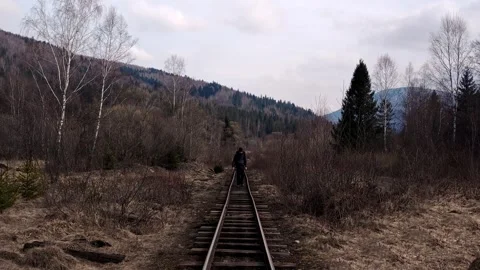 Man with Backpack Walking on Narrow Gauge Railway Tracks in Forest Stock Footage 334330009