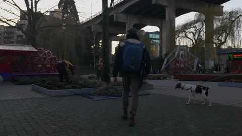Man with a backpack walking on a pavement in an industrial site passing by Stock Footage 149105118