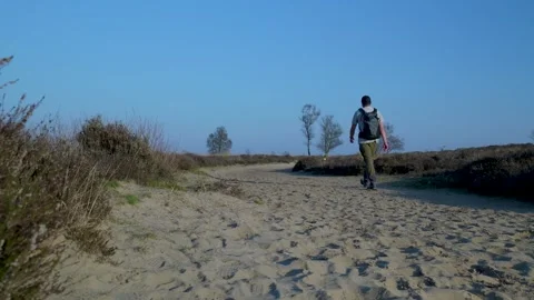 Man with a backpack walking a sandy desolate trail Video stock 335027325