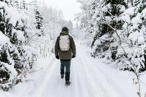 Man with backpack walking on snow covered forest. Beautiful winter time. Back Stock Photos