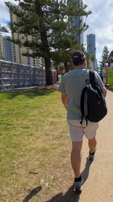 Man with Backpack Walking Toward Outdoor Event in Surfers Paradise Video stock 345017392