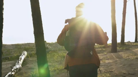 Man with backpack walking in the woods. Nice sunbeams. View from back. Stock Footage 106812005