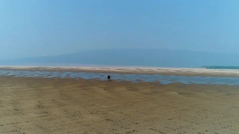 A man with a backpack walks along the bottom of a shallow river. Video stock 145718898