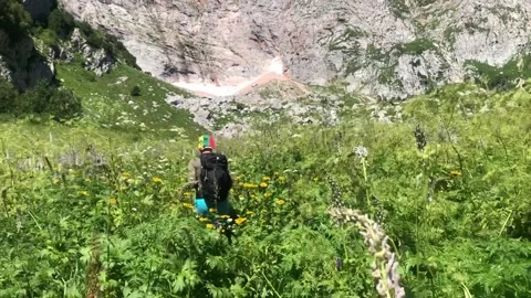 A man with a backpack walks along a mountain path Stock Footage 144116960
