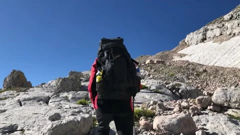 A man with a backpack walks along a mountain path Stock Footage 144116983