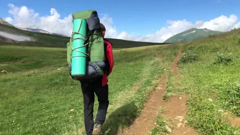 A man with a backpack walks along a mountain path Stock Footage 144117014
