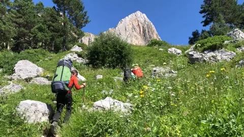A man with a backpack walks along a mountain path Stock Footage 144117056