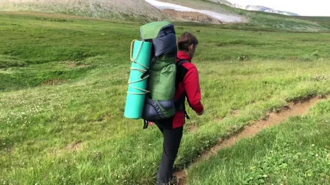 A man with a backpack walks along a mountain path Stock Footage 144117099