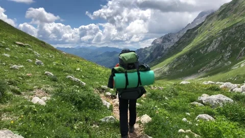 A man with a backpack walks along a mountain path Stock Footage 144117131