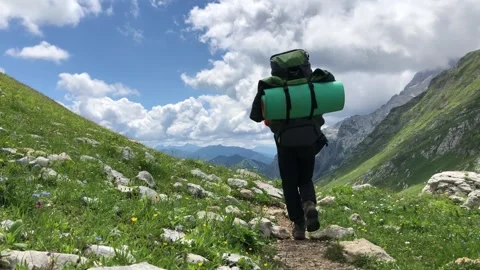 A man with a backpack walks along a mountain path Stock Footage 144117134