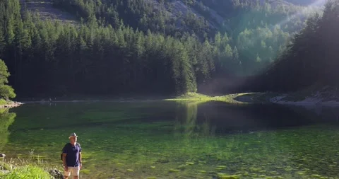 A man with a backpack walks along a mountain lake. Beautiful mountain scenery Stock Footage 247663004