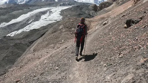 A man with a backpack walks along a narrow mountain path Stock-Footage 208437974