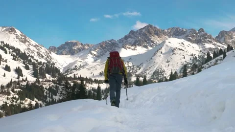 A man with a backpack walks along a path in winter in the mountains Stock Footage 233987961