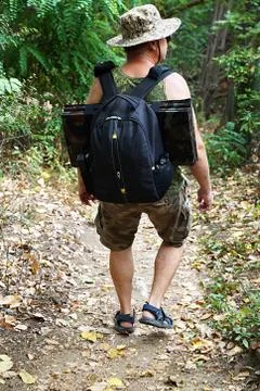 A man with a backpack walks along a path in the forest Stock Photos