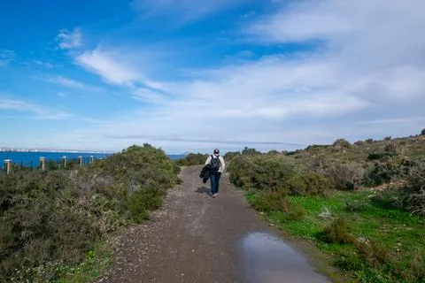 A man with a backpack walks along a path, heading towards the sea Foto stock