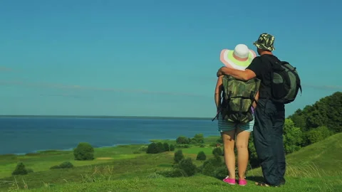 A man with a backpack walks to the edge of the mountain overlooking the lake Stock Footage 93468856