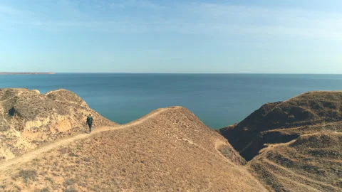 The man with backpack walks on the mountain range on the beautiful seascape Vidéo 143040641