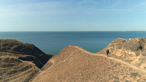 The man with backpack walks on the mountain range on the beautiful seascape Video stock 143040686
