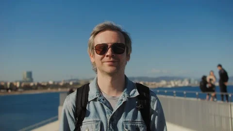 A man with a backpack walks past a building with surfer hair Stock Footage 280585782