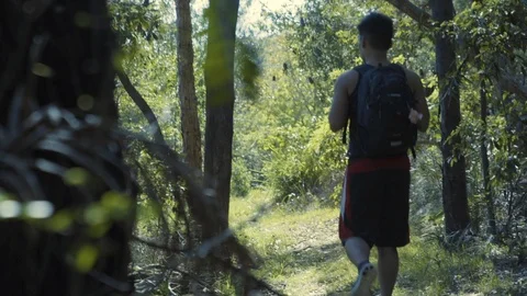 Man with backpack walks through bush on adventure Stock Footage 87543082