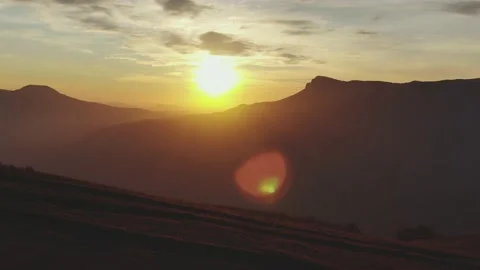 A man with a backpack watches the sunset over a forested mountain range in autum Stock Footage 151138401