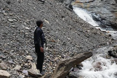 Man with a backpack wearing a black cap dressed in trekking clothes standin.. Stock Photos