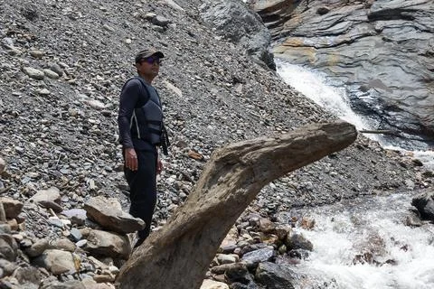 Man with a backpack wearing a black cap dressed in trekking clothes standin.. Stock Photos