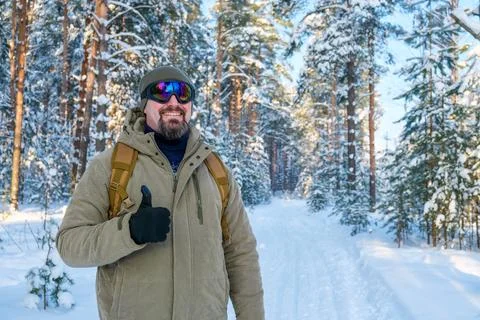 Man with backpack wearing winter ski goggles and warm coat, smiling and giv.. Stock Photos