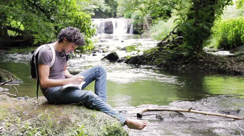 A man with a backpack writes his thoughts and notes on the nature  Stock Footage 24771059