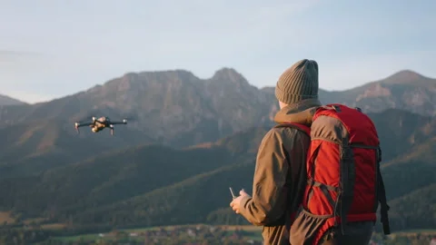 Man backpacker hiker standing on hill top launch drone, epic mountain landscape Stock Footage 283502376