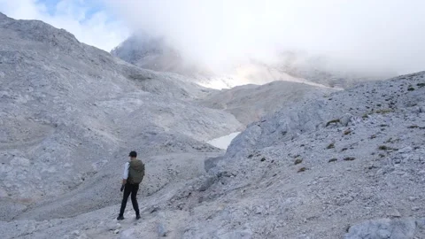 Man backpacker hiking in the alps mountain range to Triglav cloudy rocky terrain Stock Footage 161904849