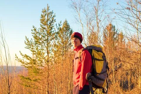 Man backpacker stands in forest at sunset in fall in yellow trees Stock Photos