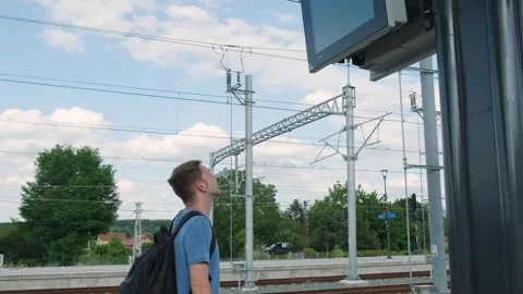 Man backpacker on the train station looking at train schedule display. Male 動画素材 256658105
