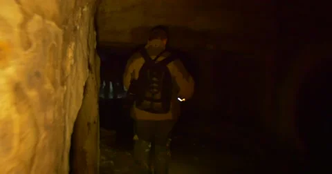 Man Backpacker is Walking Leans under Low Ceiling Wall of a Cave Close Up New Stock Footage 58649284