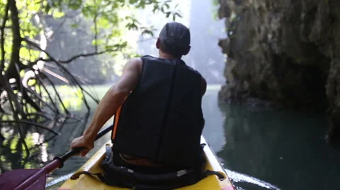 Man backside view rows on kayak in canyon Vidéo 52236475