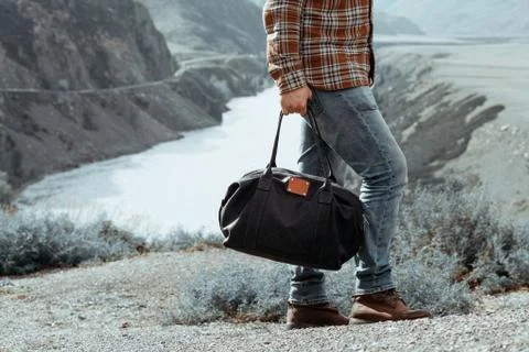 Man with bag in hand walking down a mountain road Stock-Fotos
