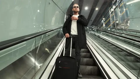 A man with baggage goes down escalator at the metro station Stock Footage 132019884