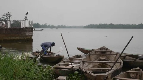Man bailing out pirogue water at the shore Stock Footage 80955790