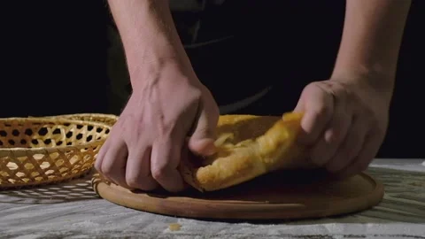 A man baker breaks freshly baked bread, puts it in a basket. Homemade cakes Stock Footage 149056161