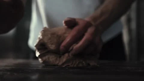 Man baker hands kneading dough on dark table. Artisan preparation of bread dough Stock Footage 344844496