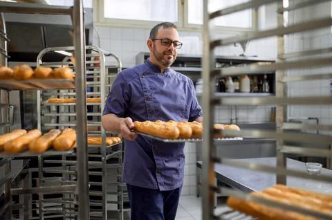 Man baker with trays of fresh bread in bakery. 스톡 사진
