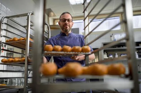 Man baker with trays of fresh bread in bakery. 스톡 사진