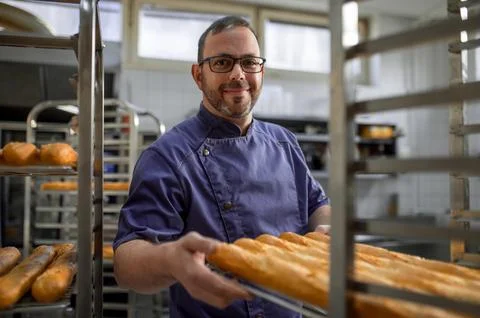 Man baker with trays of fresh bread in bakery. 스톡 사진
