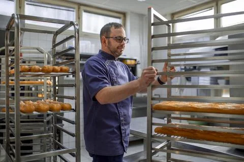 Man baker with trays of fresh bread in bakery. 스톡 사진