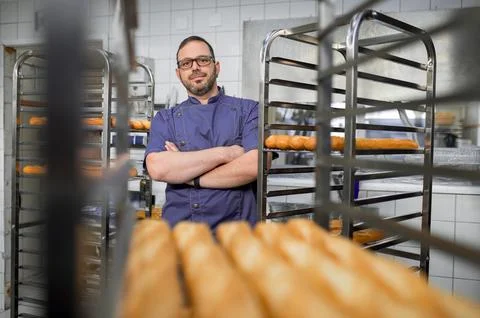Man baker with trays of fresh bread in bakery. 스톡 사진