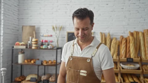 Man in bakery with shelves of bread and pastries in the background looking .. Stock Footage 285097038