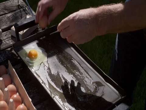 Man baking eggs on a camping on a portable stove, camping Stock Footage 76261579