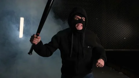A man in a balaclava and with a baseball bat in his hands threatens Stock Footage 169154652
