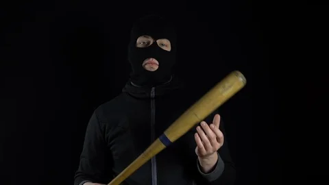 A man in a balaclava mask is standing with a baseball bat. A gangster is holding Stockbeeldmateriaal 124026564