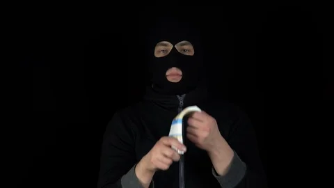 A man in a balaclava mask is standing with a bundle of rubles. The thug leafing Stock Footage 124225980